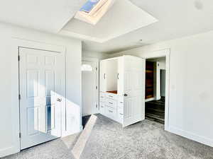 Unfurnished bedroom with a skylight, a textured ceiling, and light colored carpet
