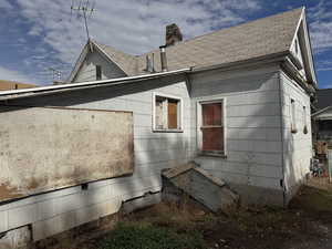 View of side of home with a chimney and a shingled roof