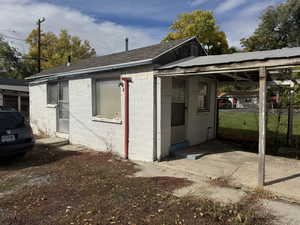 View of side of property featuring concrete block siding and roof with shingles