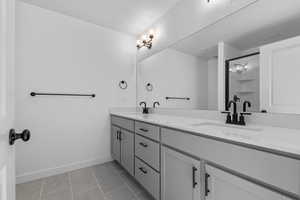 Full bathroom with a stall shower, double vanity, light tile patterned floors, and a textured ceiling