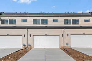 Rear view of property with concrete driveway and a shingled roof