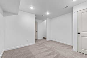 Empty room with light colored carpet and a textured ceiling