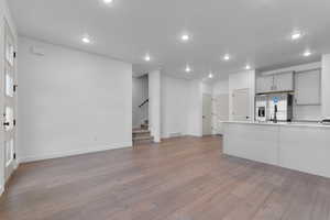 Unfurnished living room featuring light wood-type flooring, stairway, and recessed lighting