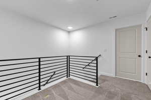Corridor featuring light carpet, an upstairs landing, and recessed lighting
