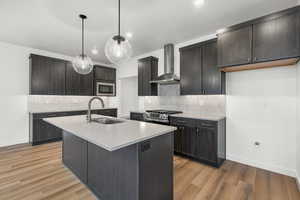 Kitchen featuring tasteful backsplash, wall chimney range hood, light wood-style floors, stainless steel appliances, and pendant lighting
