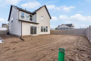 Back of property with a fenced backyard, stucco siding, and a patio area