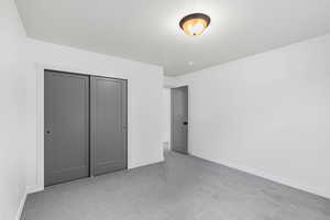 Unfurnished bedroom featuring light carpet and a closet