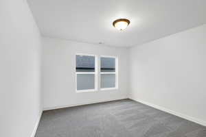 Carpeted spare room featuring a textured ceiling and baseboards