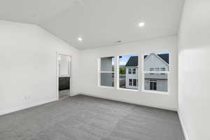 Unfurnished room featuring light colored carpet, lofted ceiling, and recessed lighting
