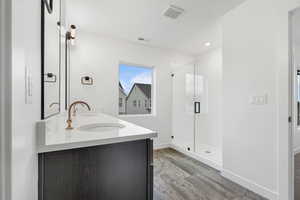 Full bathroom featuring double vanity, a shower stall, recessed lighting, and light wood-style floors
