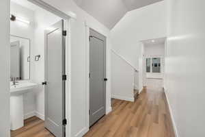 Hallway featuring light wood-style floors and vaulted ceiling