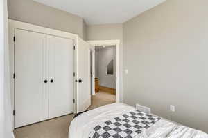 Bedroom with light colored carpet and a closet