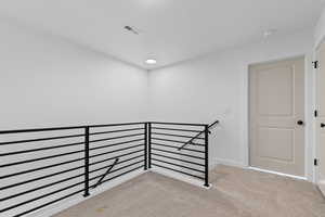 Corridor featuring light colored carpet and an upstairs landing