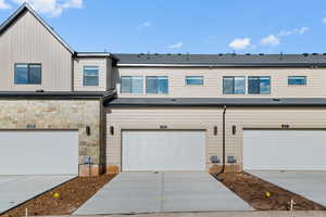 View of front of home with driveway, stone siding, board and batten siding, and a garage