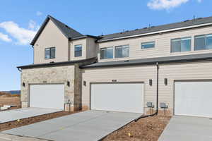 View of front facade featuring concrete driveway, an attached garage, and stone siding