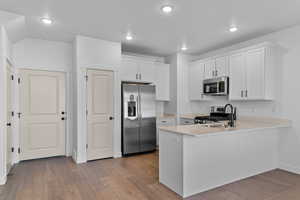 Kitchen featuring stainless steel appliances, white cabinets, light wood-style flooring, a peninsula, and recessed lighting