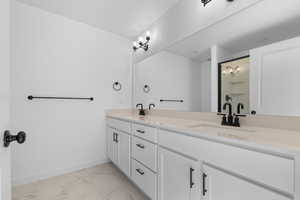 Full bathroom featuring a shower stall, double vanity, and light marble finish flooring