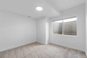 Empty room featuring light carpet and baseboards