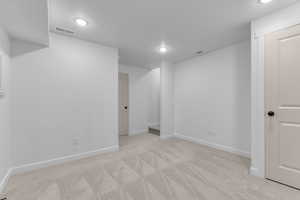 Below grade area featuring light carpet, a textured ceiling, and recessed lighting