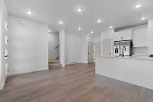 Kitchen featuring white cabinetry, light wood-type flooring, recessed lighting, stainless steel fridge with ice dispenser, and a peninsula