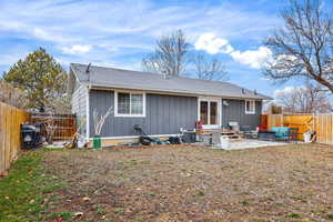 Rear view of property featuring a fenced backyard, a patio, roof with shingles, and board and batten siding