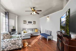 Living area with dark wood-type flooring, ceiling fan, and lofted ceiling