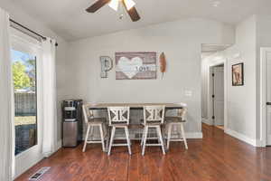 Dining space with vaulted ceiling, dark wood-type flooring, and a ceiling fan