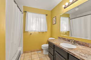Full bathroom featuring light tile patterned flooring, vanity, and shower / tub combo with curtain