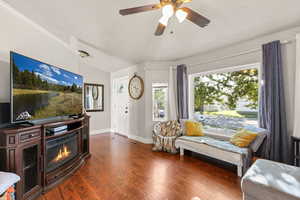Sitting room featuring wood finished floors, a ceiling fan, and a glass covered fireplace