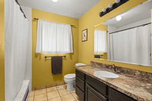 Full bath featuring vanity, light tile patterned floors, and shower / bathtub combination with curtain
