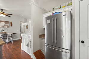 Kitchen with high end fridge, dark countertops, white cabinets, dark wood finished floors, and a ceiling fan