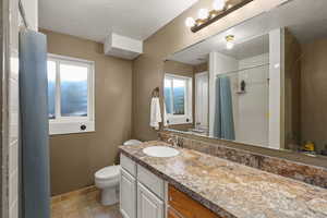 Full bath featuring light tile patterned floors, a textured ceiling, healthy amount of natural light, vanity, and a shower with shower curtain