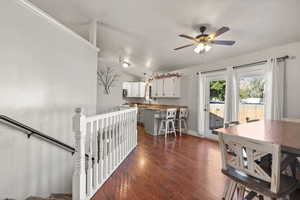 Dining room with dark wood-style flooring, vaulted ceiling, and a ceiling fan
