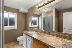 Full bath with vanity, curtained shower, healthy amount of natural light, light tile patterned floors, and a textured ceiling