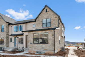 View of front facade with stone siding and a shingled roof