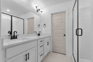 Full bathroom featuring light tile patterned floors, double vanity, a textured ceiling, and a shower stall