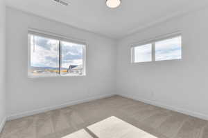 Empty room featuring light carpet and plenty of natural light
