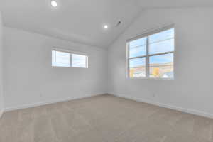 Empty room with vaulted ceiling, light colored carpet, and recessed lighting