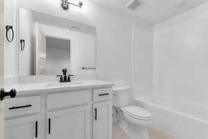 Bathroom with light tile patterned floors, vanity, shower / bath combination, and a textured ceiling