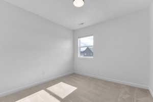 Empty room featuring light carpet and baseboards
