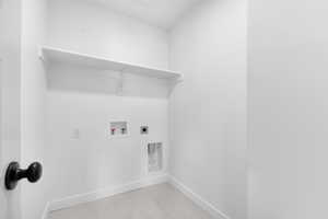 Washroom with hookup for a washing machine, electric dryer hookup, and light tile patterned floors