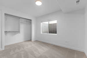 Unfurnished bedroom featuring light colored carpet and a closet