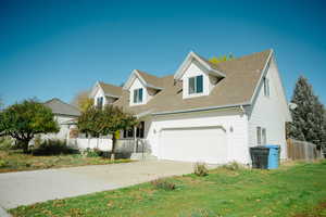 New england style home with a shingled roof, concrete driveway, a porch, and a garage