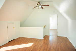 Additional living space featuring lofted ceiling, wood finished floors, and ceiling fan