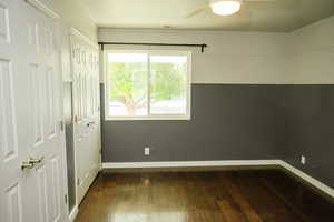 Unfurnished bedroom with multiple closets, dark wood-style flooring, and a ceiling fan