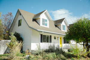 New england style home featuring covered porch and a shingled roof