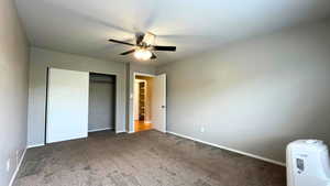 Unfurnished bedroom featuring carpet flooring, a ceiling fan, and a closet