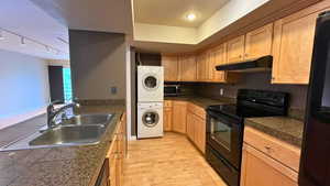 Kitchen with tile countertops, black appliances, under cabinet range hood, light wood-type flooring, and rail lighting