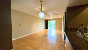 Living area featuring light wood finished floors, attic access, and rail lighting