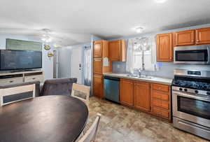 Kitchen featuring appliances with stainless steel finishes, light countertops, brown cabinets, and a textured ceiling